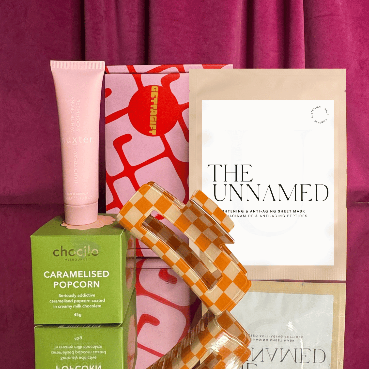Collection of beauty products including a pink tube, green box, and 'The Unnamed' product on a purple background.